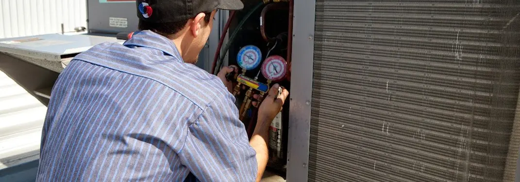 HVAC technician servicing a condenser unit in Hebron